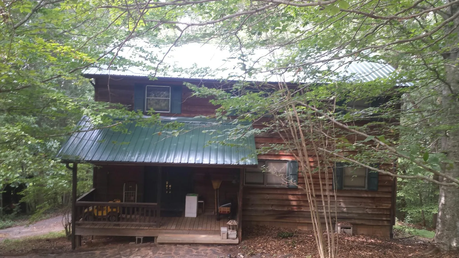 Green metal roof and covered porch on a log cabin in Lecanto