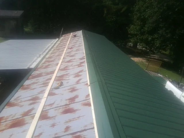 Old rusted panels beside newly installed green metal roofing — Wind Damage Roof Repair by Roofing Brothers in Lecanto