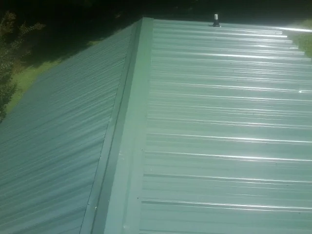New green metal panels meeting at the ridge of a roof — Flat Roof Repair work by our crew in Lecanto