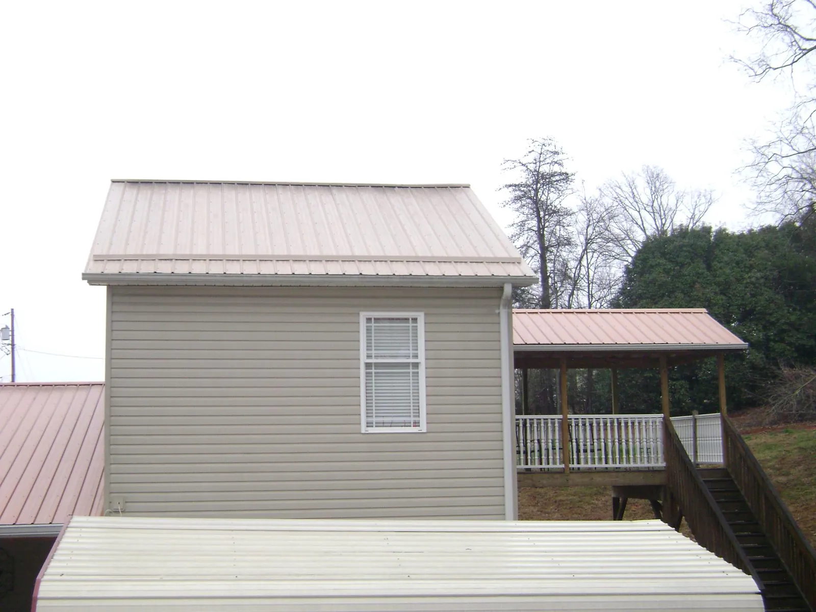 Tan metal roofs on a two story addition and attached porch, from a Roof Replacement job in Lecanto