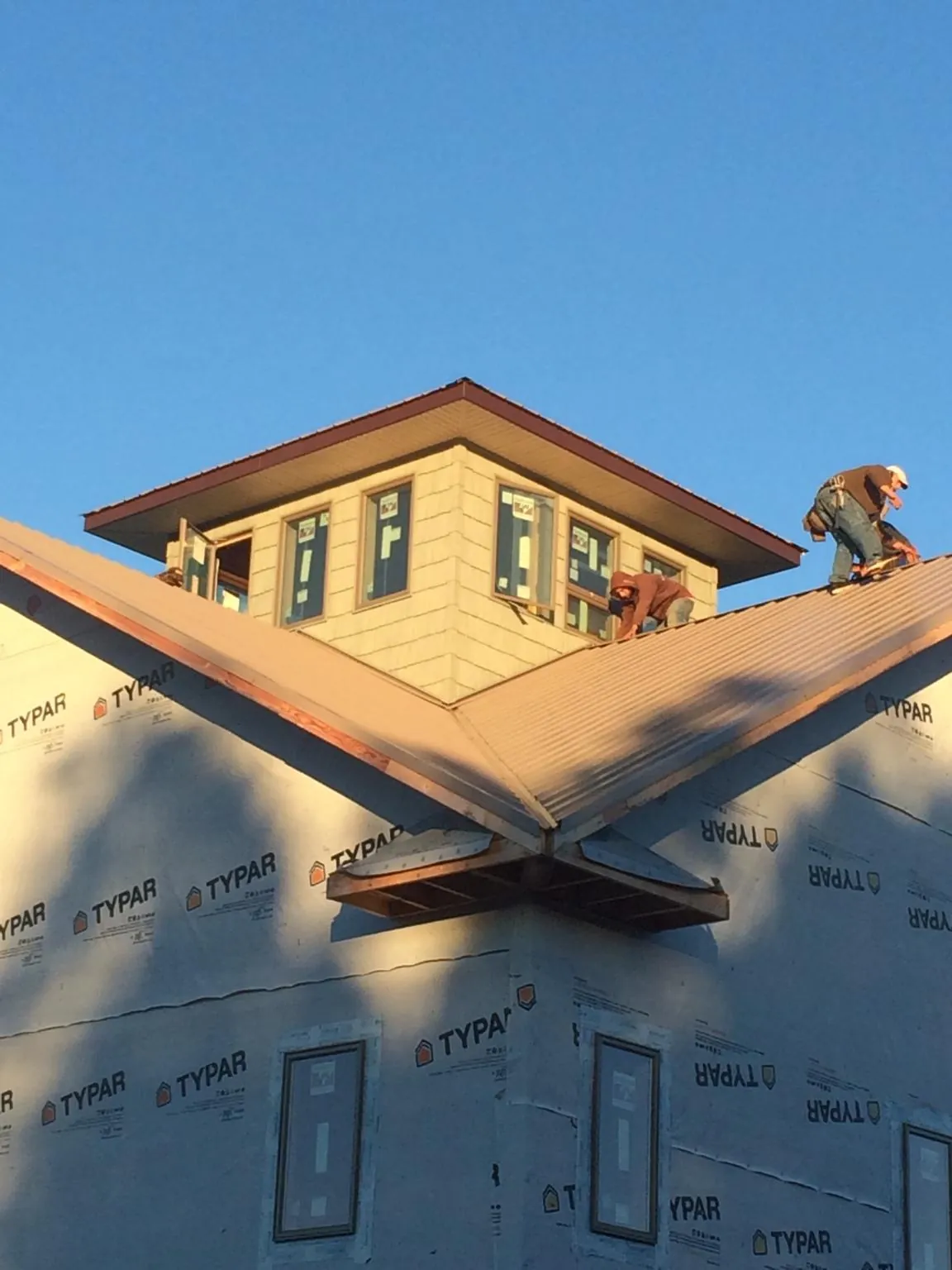 Roofers working around a rooftop cupola on a new metal roof at sunset — Roof Waterproofing in Lecanto by Roofing Brothers